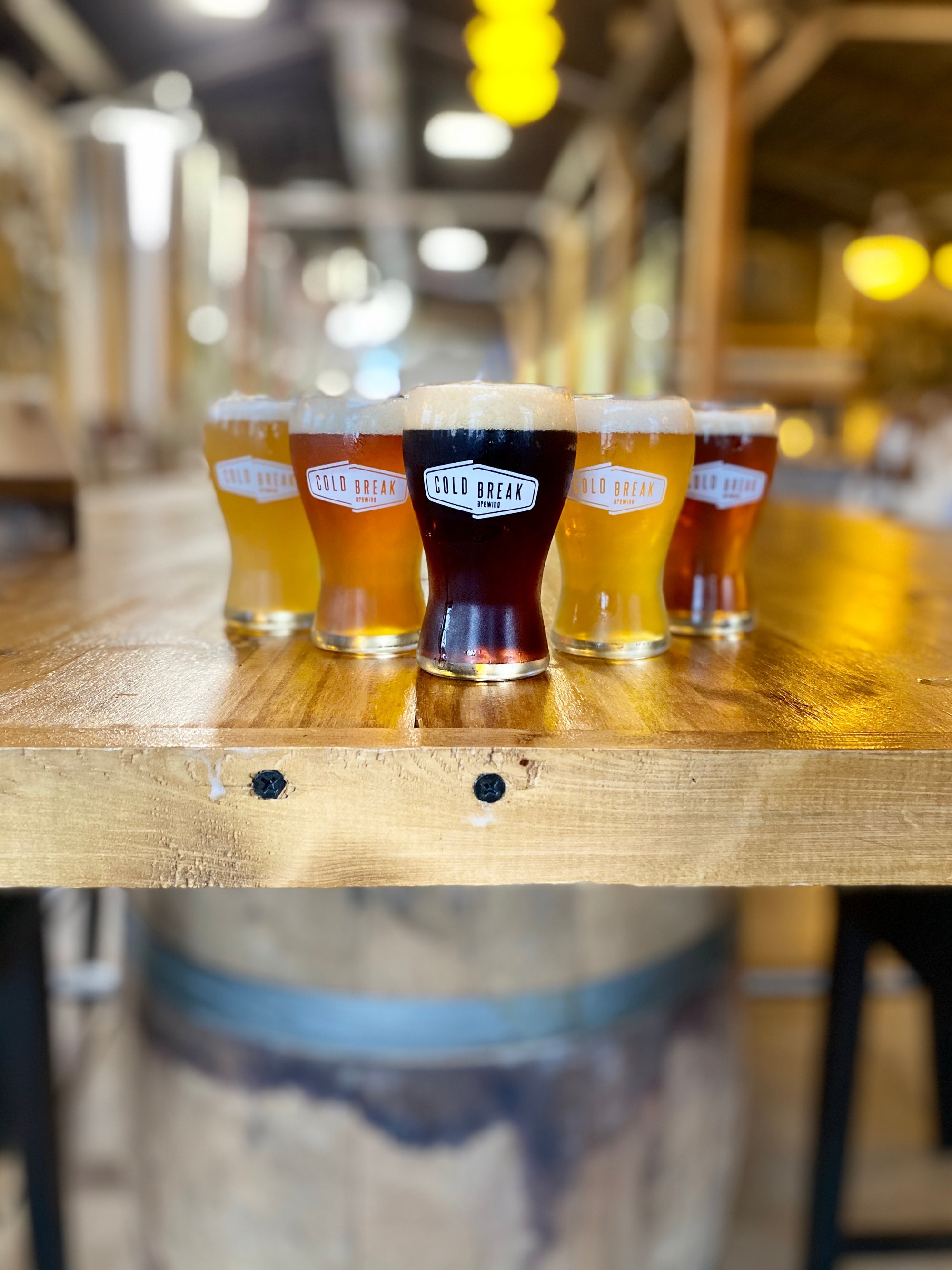 A flight of Cold Break beers on a wood table in the taproom